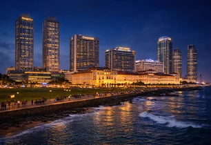 A city waterfront skyline with a colonial hotel at night